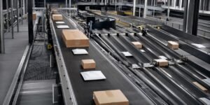 Narrow belt sorter moving parcels and cartons in a warehouse sortation line
